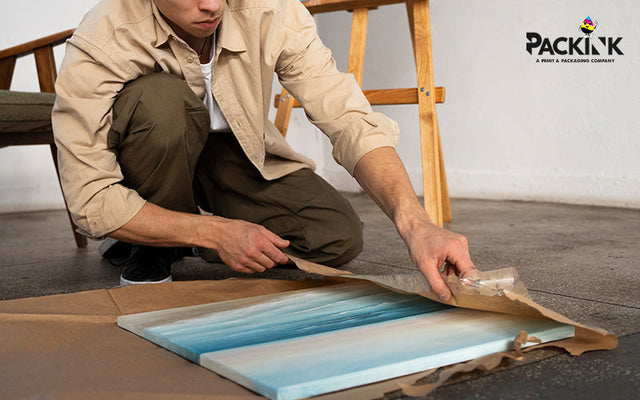 Person carefully wrapping an art print for shipping